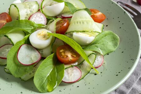 spring vitamin salad with fresh vegetables on a wooden table.の写真素材