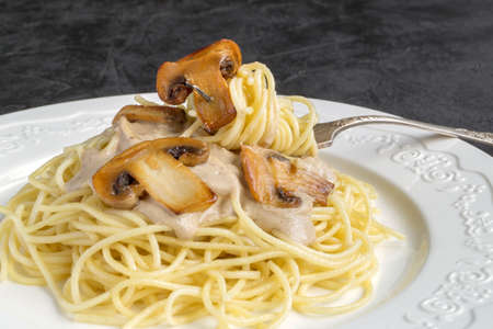 Spaghetti with mushrooms in cream sauce. on dark backgroundの写真素材