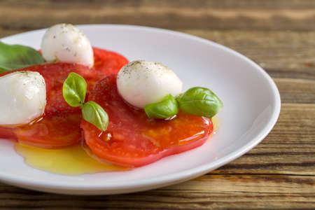 Caprese salad with ripe tomatoes and mozzarella with fresh Basil leaves. Italian food.の写真素材