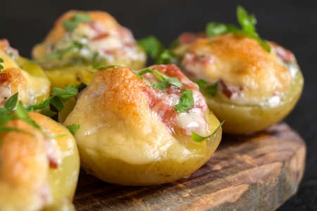 Hot baked stuffed potatoes with cheese, bacon, parsley on a wooden Board.の写真素材