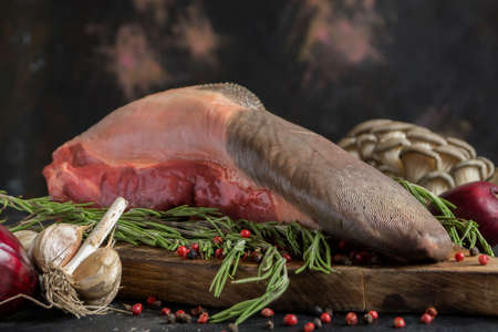 raw beef tongue on a chopping Board. with spices