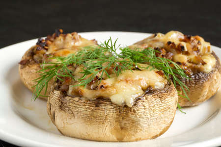 mushrooms baked with cheese and onions. on dark background.の写真素材