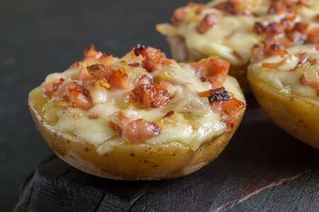 Hot baked stuffed potatoes with cheese, bacon, parsley on a wooden Board.の写真素材