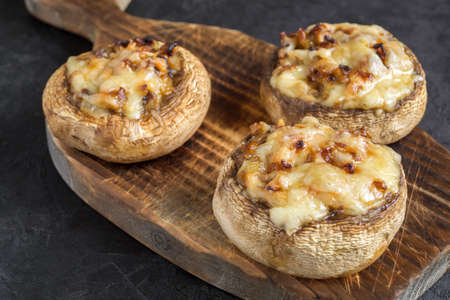 mushrooms baked with cheese and onions. on dark background.の写真素材