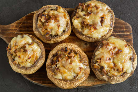 mushrooms baked with cheese and onions. on dark background.の写真素材