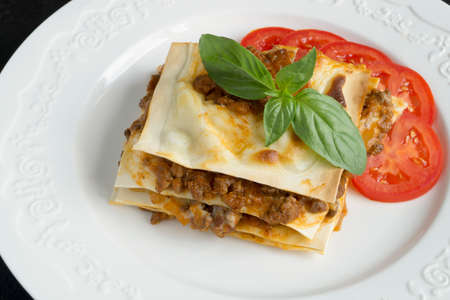 Meat lasagna with basil. on a white plateの写真素材