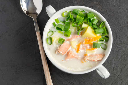 Salmon soup with cream, potatoes, carrots and dill. on a black background.の写真素材