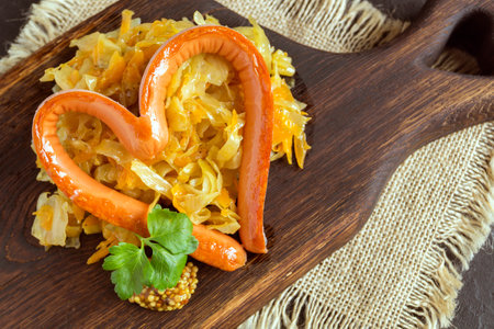 braised pickled cabbage with grilled sausage in the shape of a heart. on a wooden boardの写真素材