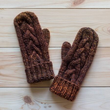 Mittens knitted in dark brown wool on wooden backgroundの写真素材