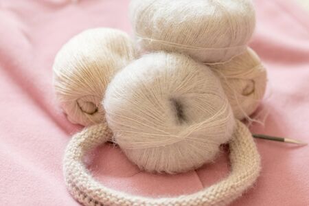 A coil of soft beige wool for knitting on a pink backgroundの写真素材