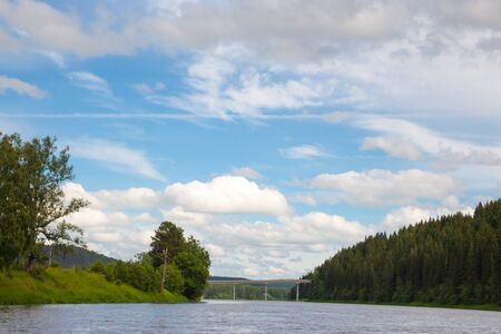 The high water on the river Ufa in the summer. Green trees and blue sky with clouds.の写真素材