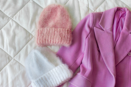 Women's draped pink coat next to two fluffy caps of different colorsの写真素材