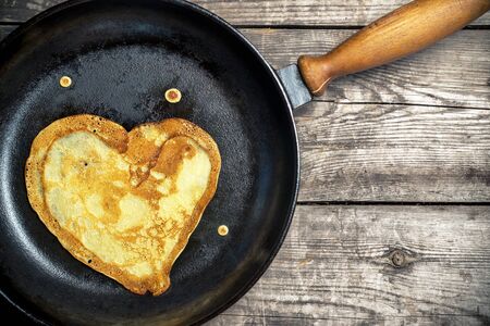 Fried pancakes - heart on a cast iron skillet . Top view .の写真素材
