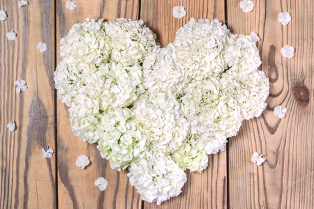Heart made of white flowers on a wooden background. Flat lay. Shallow DOF.の写真素材