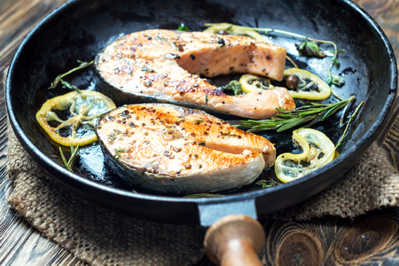 Salmon steak, fried with herbs, pepper and lemon. In a cast iron skillet. Shallow DOFの写真素材