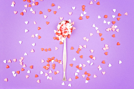 Vintage spoon with small pink, white, red sweet hearts on pastelの写真素材