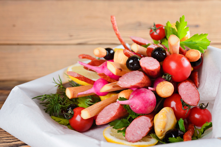 Smoked sausage, cheese, vegetables and greens, collected in a bouquet. Option gift man. On wooden background.の写真素材