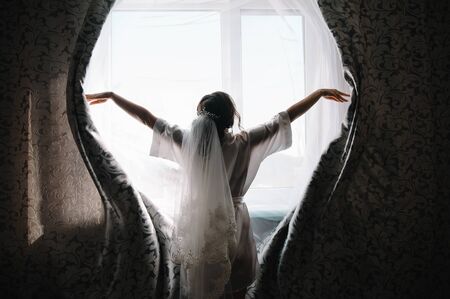 Bridesmaid preparing bride. Bridesmaid helps fasten a wedding dress the bride before the ceremony. Luxury bridal dress close up. Best wedding morning.の写真素材