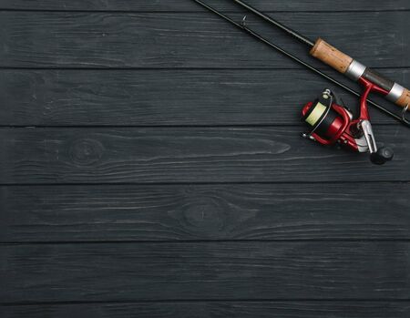 Fishing tackle - fishing spinning, hooks and lures on darken wooden background. Top view.の写真素材