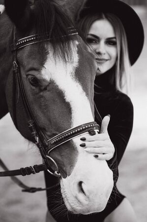Young woman physiotherapist taking care a brown horse. Woman making a treatment in the shoulder, crest, forehead, muzzle and chin groove.の写真素材
