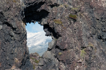 The west of Iceland, at the western end of the peninsula Sneifellsnes, in the lava field of Hellnar, hole in the lava overlooking the snow-covered slope of Sneifellsjoekullの写真素材