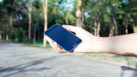 hand holding smartphone against on smooth background.