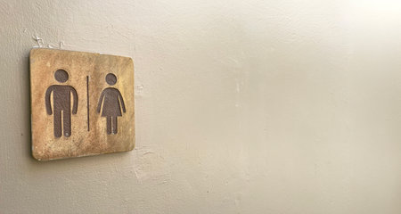 Modern public bathroom sign on the cement wall. Wooden bathroom sign on a white wall