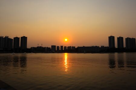 CItyscape modern apartment building near a lake under sunset twilight with cloud sky background with...