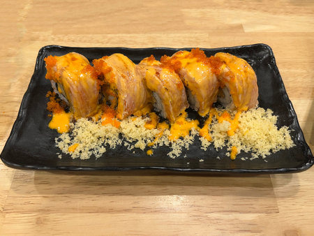 Sushi roll on a black plate on a wooden table in a Japanese restaurantの写真素材