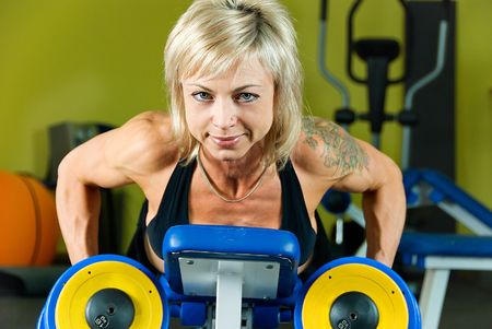 young woman bodybuilder does exercise with dumbbellsの写真素材