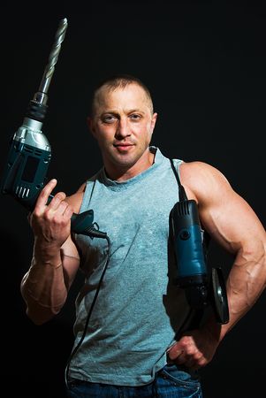 young strong man with drill and bolgarcka on black background