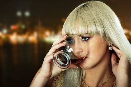 beauty blond girl with wine on night city backgroundの写真素材