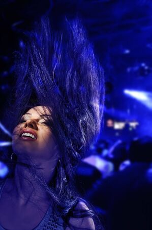 brunette girl dancing with colorful club lights background の写真素材