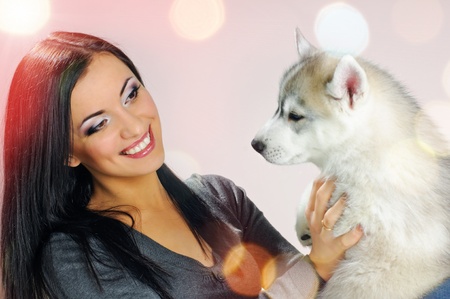 playing woman with puppy of siberian haski on pink background with confetti