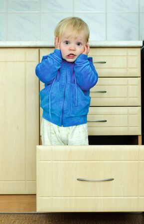 white haired little boy in the kitchen cabinet の写真素材