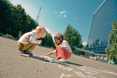 little boy and girl with crayons, they drawing on the asphaltの写真素材