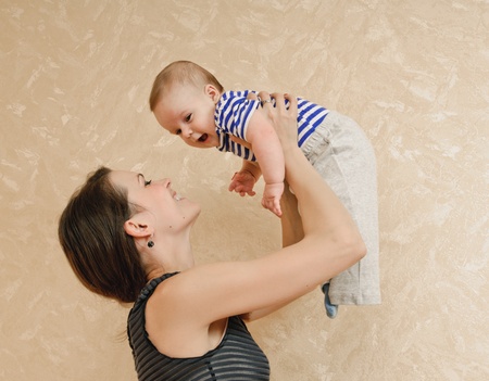 young mother and her baby in the room about wall with wall-paper