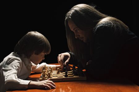 father and son having game of chess in low keyの写真素材