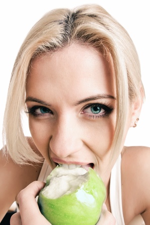 portrait of beautiful peroxide blonde with green apple girl on whiteの写真素材