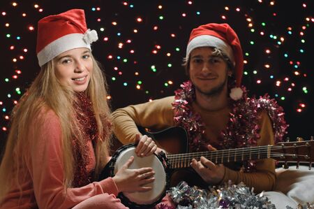 young happy couple makes music on garland background, focus is on girlの写真素材