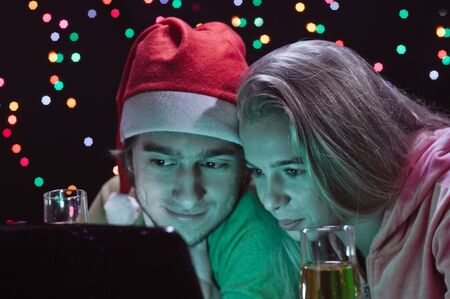 young happy couple about laptop on garland backgroundの写真素材