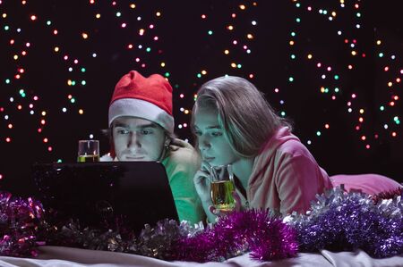 young happy couple about laptop on garland backgroundの写真素材