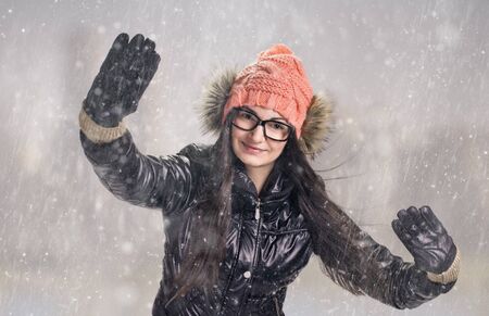 beautiful brunette in winter with snowstorm on city backgroundの写真素材