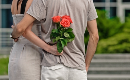 embracing young couple with rose from back の写真素材