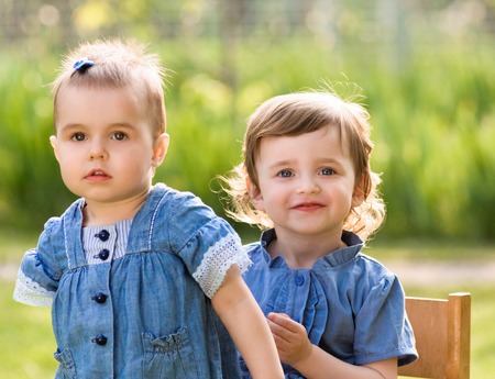 Children sitting on chair in summer parkの写真素材