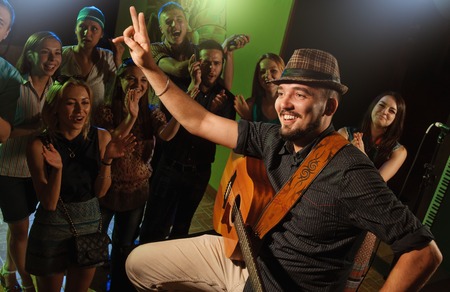 singer and guitarist performing on stage in a club communicates with cheering crowdの写真素材