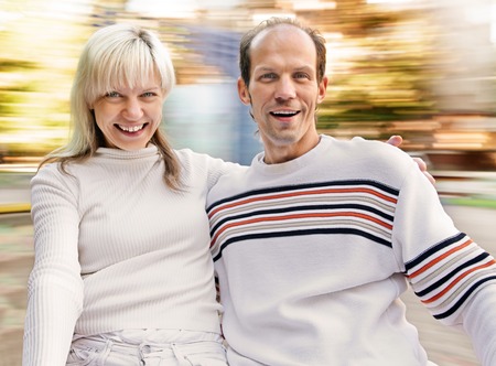 Laughing couple enjoy in riding On Roundabout. natural motion blur
