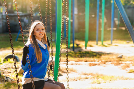 beautiful girl on a swing in the park. autumnの写真素材