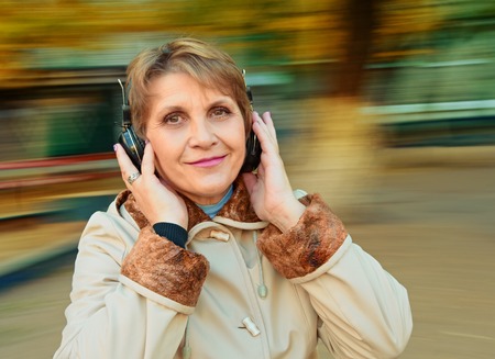 Senior Woman having fun with music headphones. background with natural motion blurの写真素材