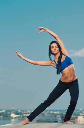 yoga fitness and lifestyle concept - woman doing sports outdoors on the house-topの写真素材